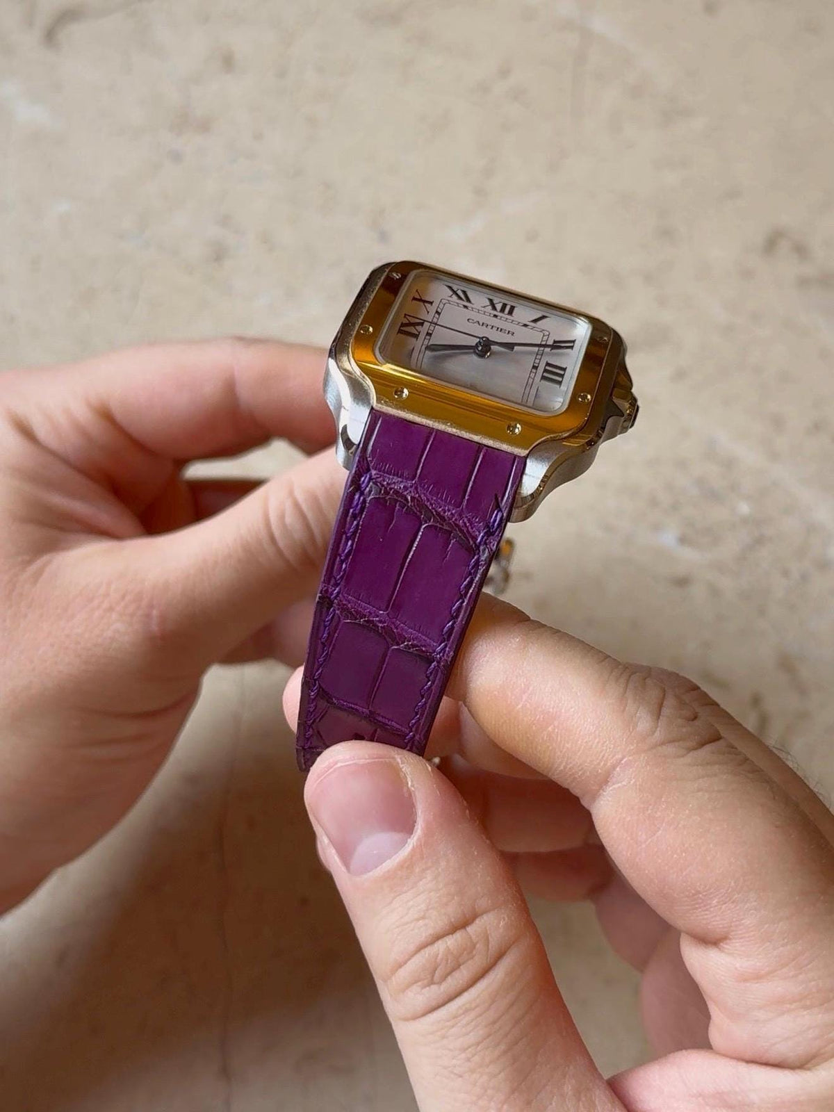 Cartier Santos with a handmade matte purple alligator leather strap, held in the hand