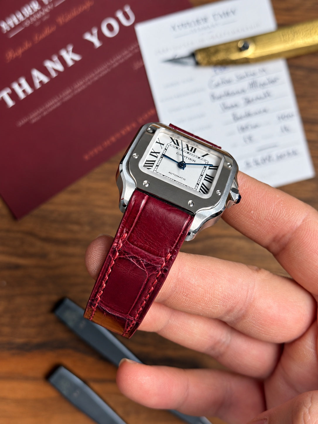 Bordeaux alligator strap on a Cartier Santos, with the strap card and thank-you note