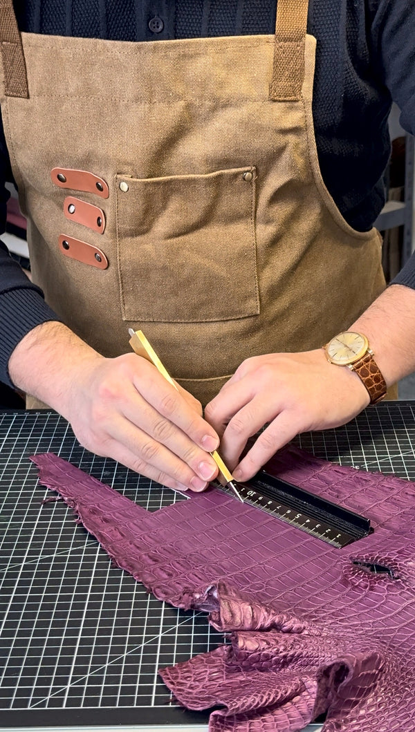 Marking a purple alligator hide by hand at the workbench
